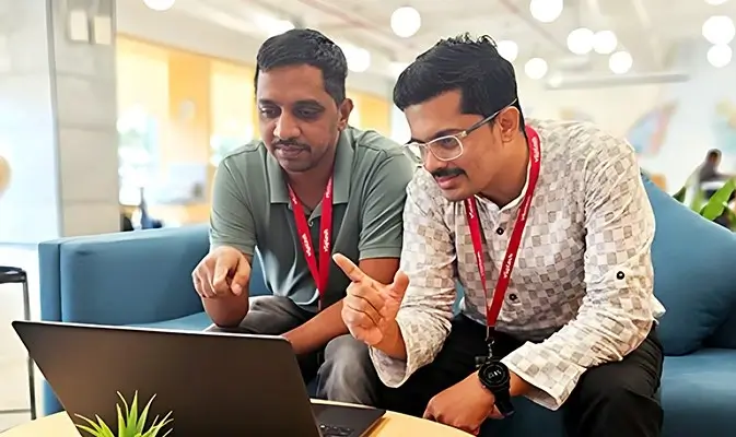 Two men working on a laptop together.